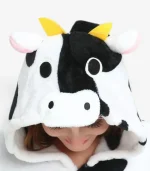 Close-up of the cow onesie hood featuring plush horns, ears, and a cute cow face.
