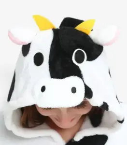 Close-up of the cow onesie hood featuring plush horns, ears, and a cute cow face.