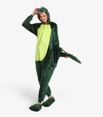 Woman smiling playfully and holding the tail while wearing the comfortable Dinosaur Onesie For Adults.